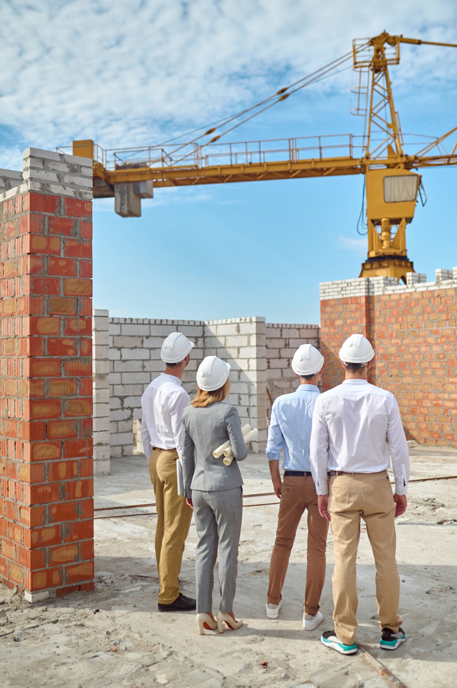 INICIO four people in protective helmets inspecting the building area